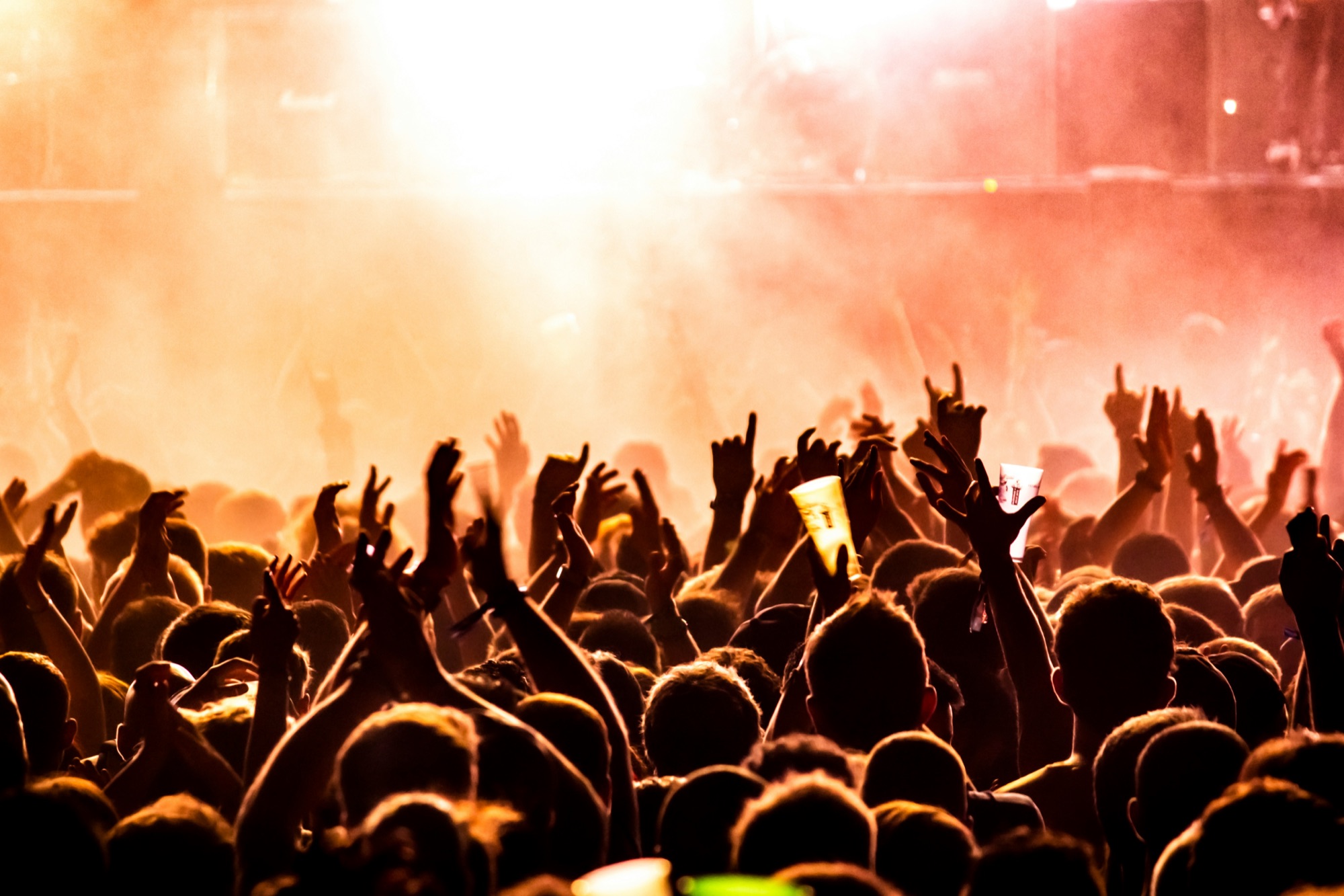 A crowd with raised hands in front of a stage