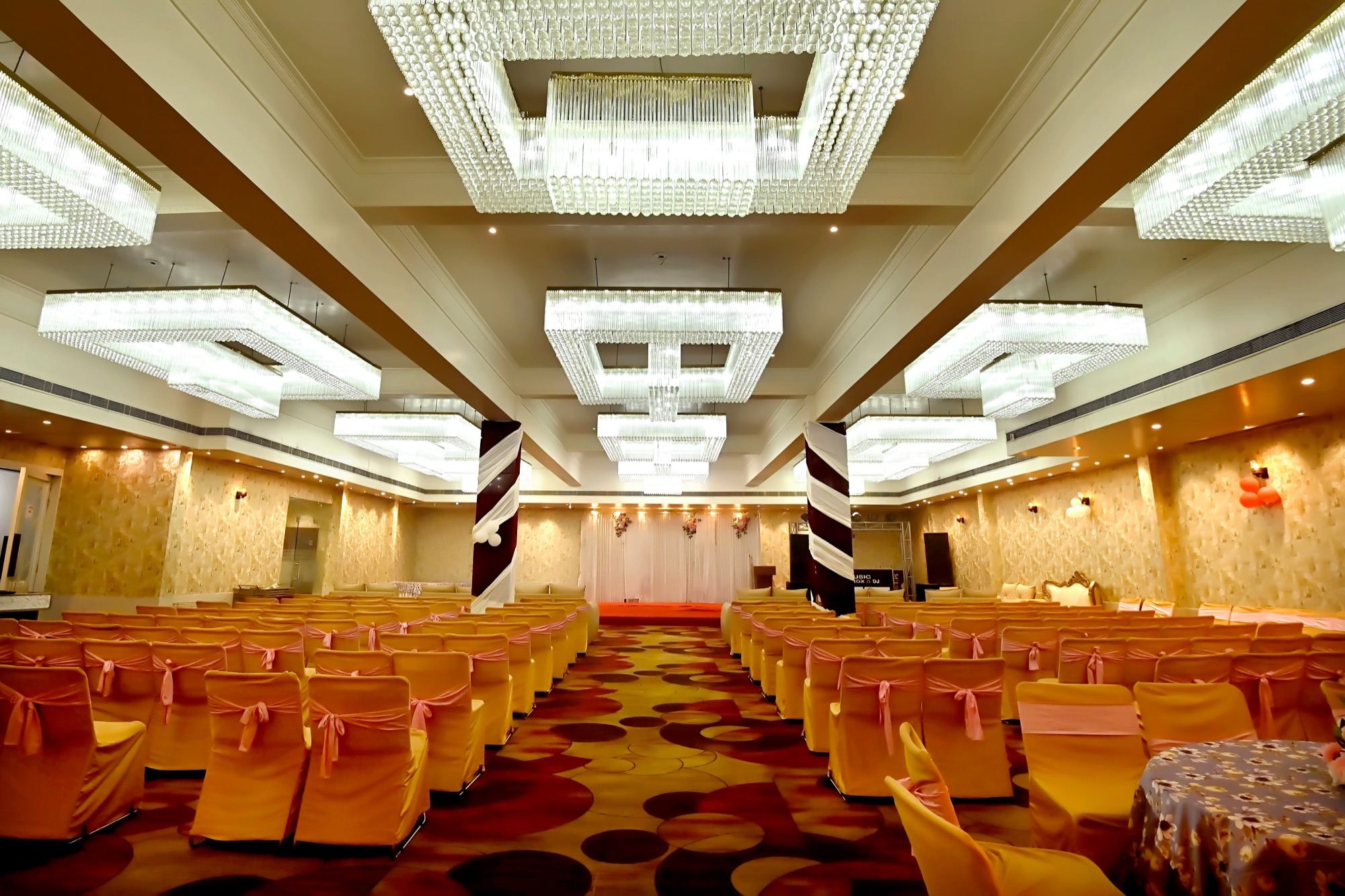 A banquet hall set with rows of dressed chairs